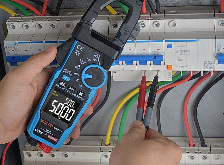 An electrician is using the test leads of a Metek multimeter to measure the main power switch.